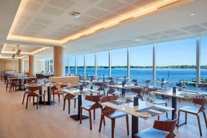 珀斯Doubletree By Hilton Perth Waterfront的一间带桌椅的海景餐厅