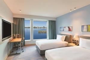 珀斯Doubletree By Hilton Perth Waterfront的酒店客房设有两张床、一张书桌和一个窗户。