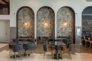 卡尔斯巴德The Cassara Carlsbad, Tapestry Collection By Hilton的餐厅设有4个拱形窗户,配有桌椅