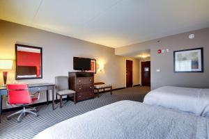 利兹伯明翰/利兹汉普顿酒店的酒店客房设有两张床、一张桌子和一台电视。