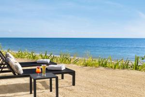 坎昆Hilton Cancun, an All-Inclusive Resort的海滩上的长凳,带两杯饮料