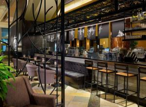 休斯顿希尔顿美洲休斯顿酒店 的餐厅设有酒吧,配有桌椅