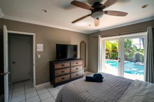 劳德代尔堡Tropical Paradise的一间卧室配有一张带吊扇的床和一台电视。