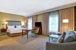 查尔斯顿Hampton Inn & Suites Charleston Airport的酒店客房配有一张床、一张书桌和沙发。