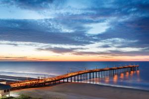 默特尔比奇DoubleTree Resort by Hilton Myrtle Beach Oceanfront的日落时分,一个码头延伸到海洋上
