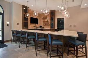 奥兰多Homewood Suites By Hilton Orlando Flamingo Crossings, Fl的一个带酒吧的大厨房,酒吧配有椅子和灯