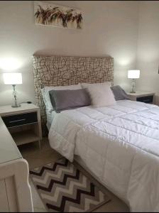 特尔马斯德里奥翁多Infinit Home Duplex entero的一间卧室配有一张大床、两张桌子和两盏灯。