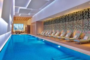 沙迦DoubleTree by Hilton Sharjah Waterfront Hotel And Residences的一个带躺椅的游泳池和一个游泳池