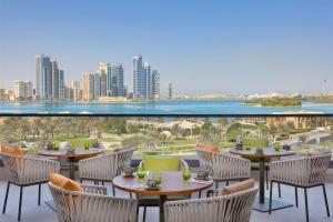 沙迦DoubleTree by Hilton Sharjah Waterfront Hotel And Residences的一个带桌椅的庭院,享有城市美景。