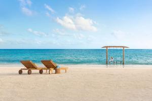 马累Hilton Maldives Amingiri Resort & Spa的海滩上带两把椅子和凉亭的海滩
