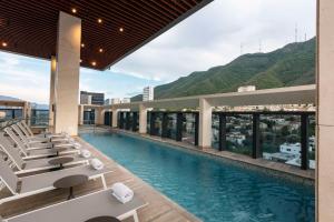 蒙特雷Hilton Monterrey Valle的酒店游泳池设有躺椅,背景为山脉