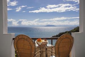 布希奥斯科隆纳园酒店的阳台配有一张桌子和两把椅子,享有海景