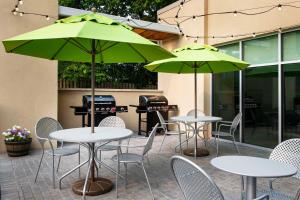 列克星敦列克星敦大学/医学中心希尔顿欣庭套房酒店的庭院里配有两张带绿伞的桌椅