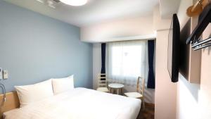 茅崎市Toyoko Inn Chigasaki Shiyakusho的卧室配有白色的床和窗户。