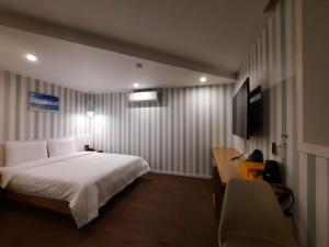 釜山Rein Hotel Busan Yeonsan的一间卧室配有一张床、一张书桌和一台电视