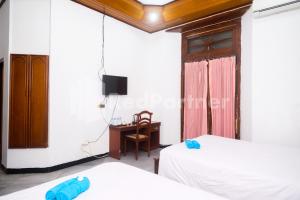 SentoolHotel Limaran 1 Syariah Malioboro Mitra RedDoorz的客房设有两张床和一张书桌