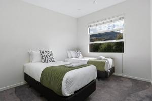 皇后镇Whakata on McBride的一间卧室设有两张床和窗户。