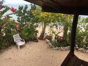苏梅岛Bangpo Village Tiny Country Beach House的海滩上摆放着白色椅子,鲜花盛开