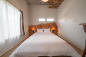 MinamichoIchi The Hostel的一间卧室配有一张带白色床单的床和一扇窗户。