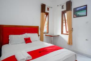 沃诺索博RedDoorz near Alun Alun Wonosobo 2的窗户客房内的一张红色和白色的床