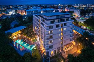 清迈奈帕大服务公寓的一座白色的建筑,在晚上在城市前方有一个游泳池