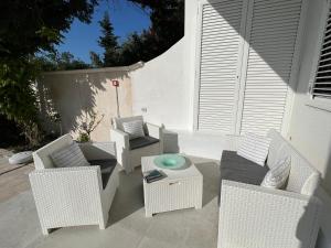 托雷奇安卡Casa Flavia的庭院配有白色藤椅和桌子
