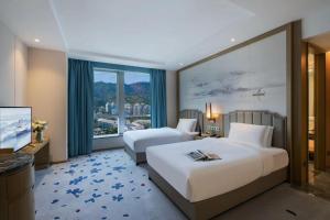 深圳深圳海上世界九州瑾程酒店的酒店客房设有两张床和大窗户。