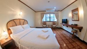 清迈隆格鲁安酒店的卧室配有一张白色大床和一张书桌