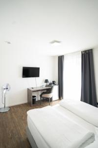菲尔恩海姆AP Hotel Mannheim Viernheim的一间卧室配有一张床和一张书桌及电视