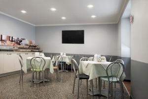 热那亚阿萨罗堤酒店的一间带桌椅和电视的用餐室