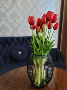 塔什干IZZA PALACE Hotel的一张桌子上装有红色郁金香的花瓶