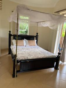 KinkiziRafiki Safari Lodge Bwindi的一间卧室配有一张天蓬床和窗户
