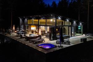 LohjaVilla Padel - Premium Lakeside Residence & Grounds的一座大型玻璃房子,晚上设有游泳池