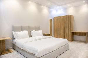 AR RummanahLuxurious Family Apartments 15Mins Drive to Al-Masjid Nabawi - Qaswarah residence的卧室配有一张白色大床和木制橱柜。