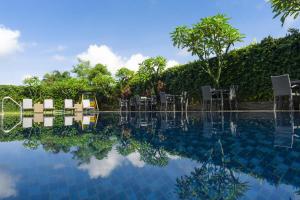 玛琅索拉斯玛琅酒店的一个带桌椅和树木的游泳池