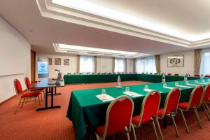 卡尔达诺阿尔坎波贝斯特韦斯特卡瓦利瑞德拉科洛纳酒店的一间会议室,配有绿色桌子和红色椅子