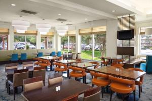 休斯顿休斯敦/布什洲际机场希尔顿花园酒店的餐厅设有木桌、椅子和窗户。