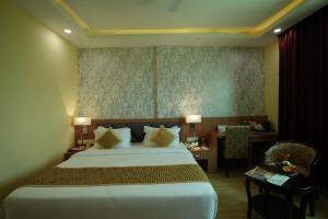巴特那The Royal Bihar的酒店客房设有一张大床和一张书桌。