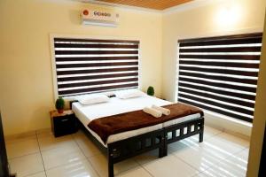 KottakkalDAYA AYURVILLAGE的一间卧室设有一张床和两个大窗户
