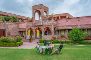 焦特布尔The Hosteller Heritage Palace, Jodhpur的一群人坐在大楼前的桌子上