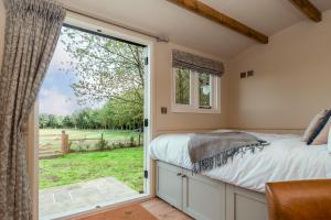 埃文河畔布拉德福Great Ashley Farm Bed and Breakfast & Shepherds Huts的一间卧室设有一张床和一个滑动玻璃门