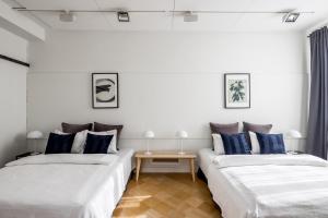 赫尔辛基Elegant City Home的配有白色墙壁和蓝色枕头的客房内的两张床