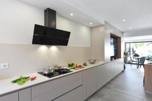 马斯帕洛马斯Duplex Los Tinos II 32 by VillaGranCanaria的厨房配有白色橱柜和壁挂式平面电视。