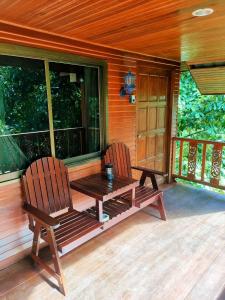 班泰Family Resort的小屋门廊上设有两把椅子和一张木桌