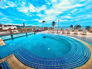 芭堤雅市中心芭提雅AA酒店的一个带椅子的游泳池,背景是大海