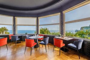 埃特勒塔多米楼酒店的餐厅设有桌椅和大窗户。