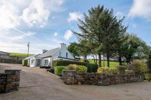 莱特肯尼Traditional Cottage with Private Hot Tub in the Heart of Donegal的白色的房子,有石墙和树木