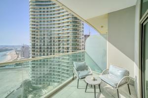 阿布扎比Beach Towers A, Reem Island Abu Dhabi - Mint Stay的一个带两把椅子和一张桌子的阳台和一座高高的建筑