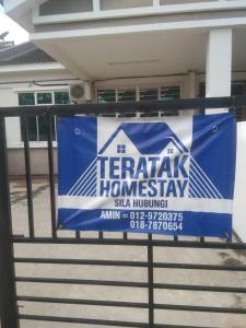 樟仑Teratak Homestay的房屋前的栅栏上的一个标志