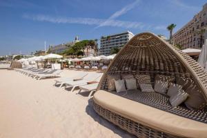 戛纳Le Madrilien & Terrasse & Clim & 400M Croisette的海滩上的藤床,带椅子和遮阳伞